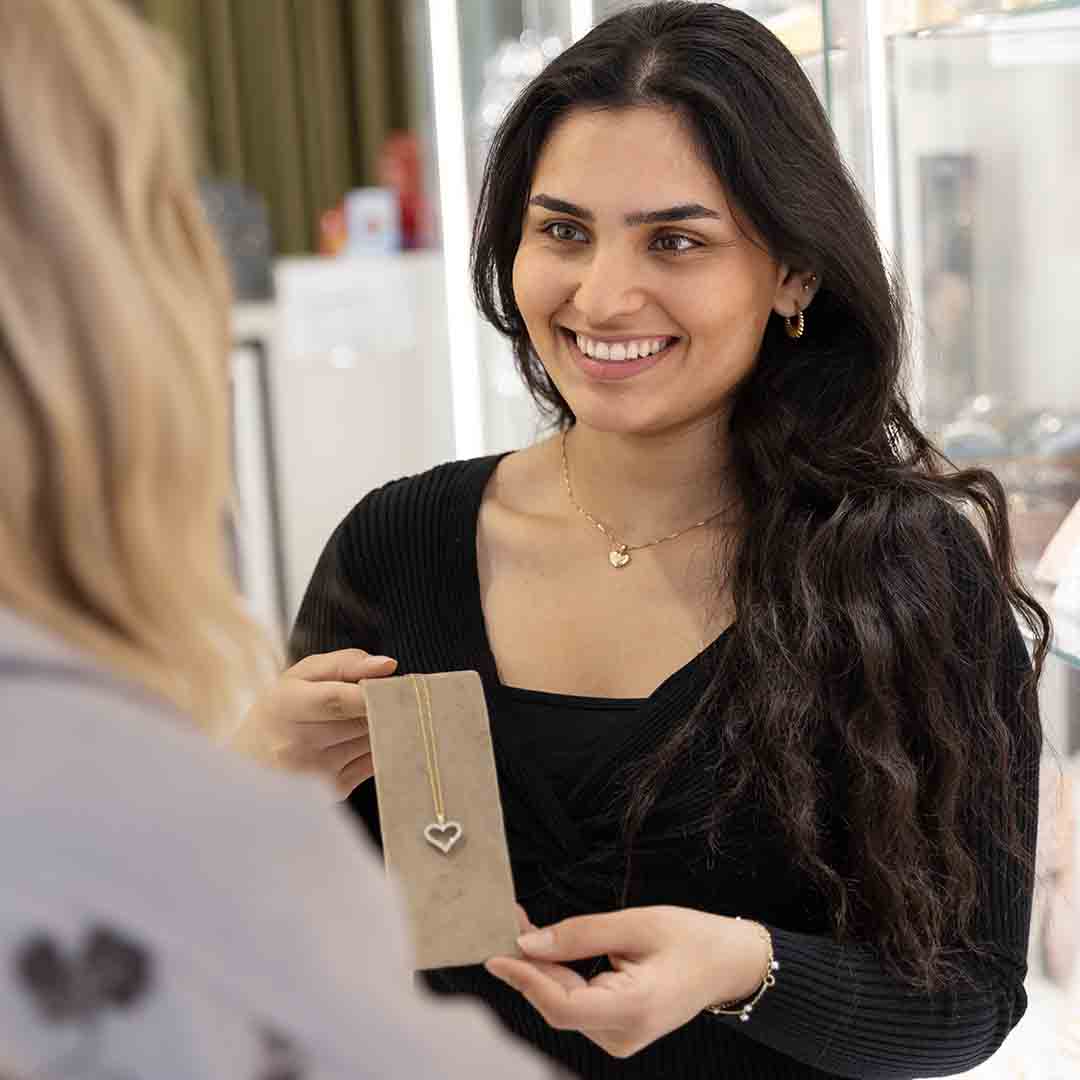 Employee from Plaza in Frederiksberg shows a customer a heart necklace.